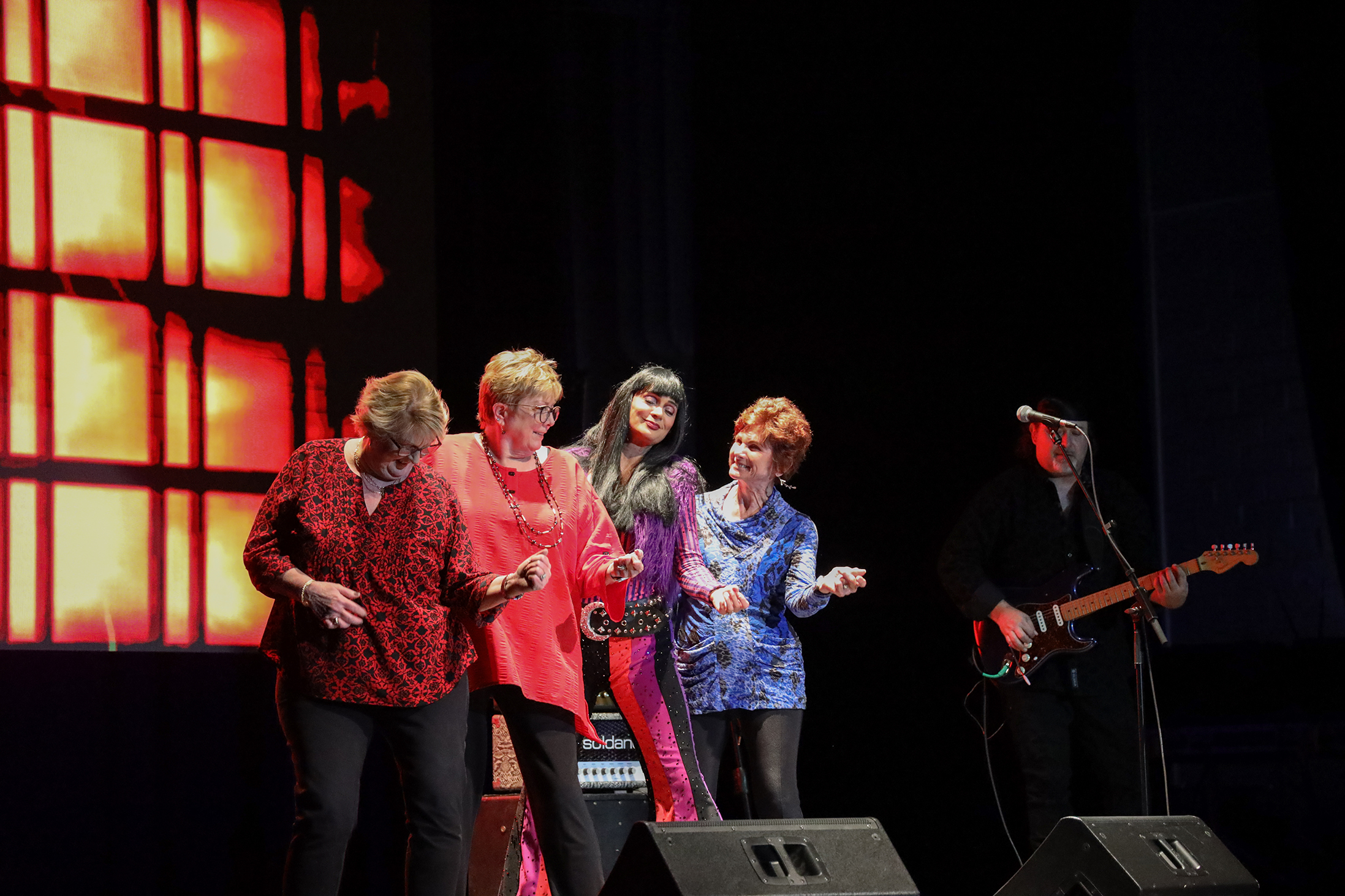 Audience members participating onstage with Cher Tribute singer.